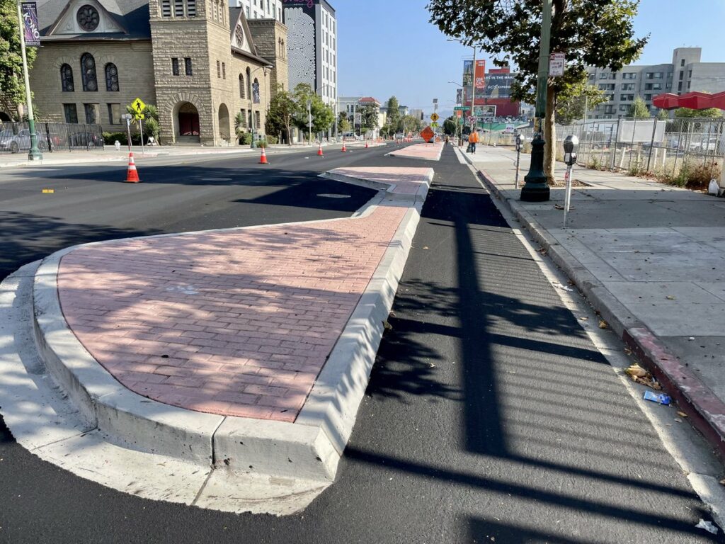 Photo of curbside bikeway protected by concrete islands on Telegraph Ave in Oakland