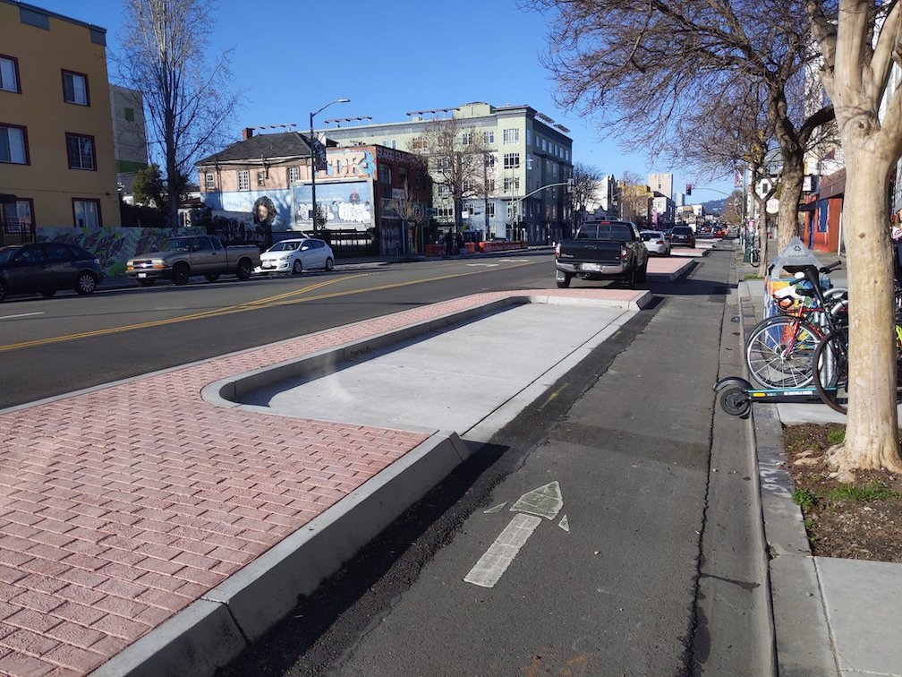 Photo of curbside bikeway protected by concrete islands on Telegraph Ave in Oakland