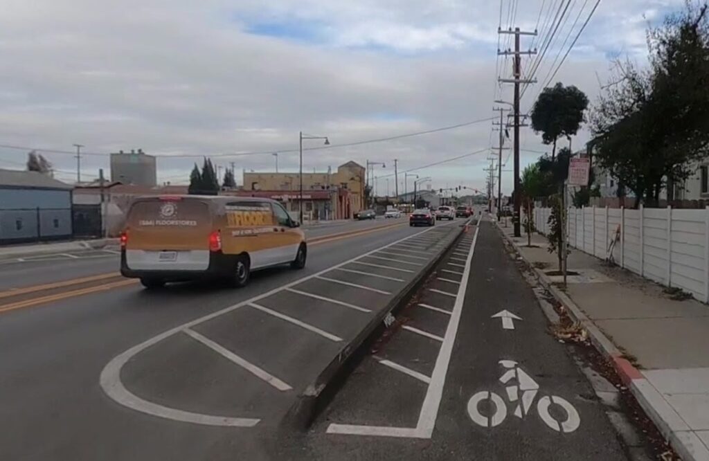 Photo of curbside bike lane on Rumrill Blvd in San Pablo CA, separated from car traffic by an asphalt curb