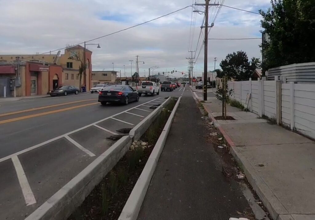 Photo of curbside bike lane on Rumrill Blvd in San Pablo CA, separated from car traffic by a planted median