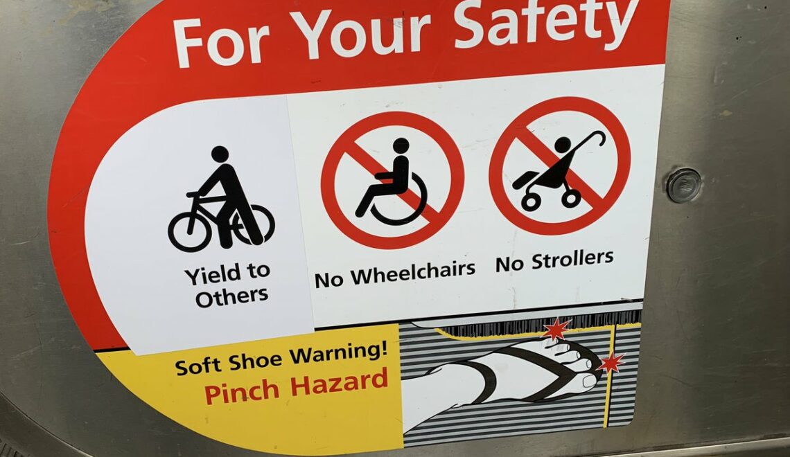 Photo of a sticker on a BART escalator. Text: "For Your Safety Yield to Others No Wheelchairs No Strollers Soft Shoe Warning! Pinch Hazard"