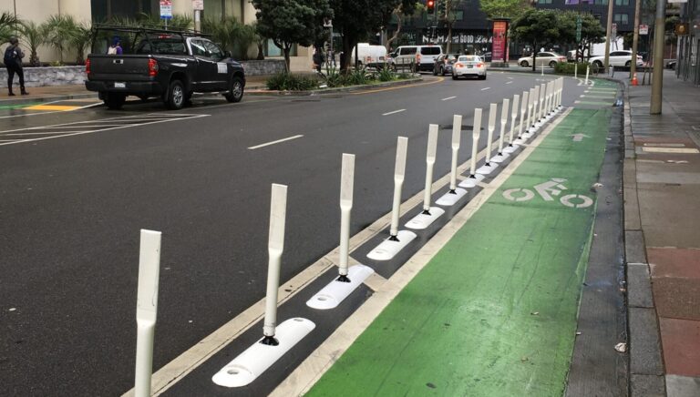 example photo of plastic curb and post assemblies along a green painted bike lane