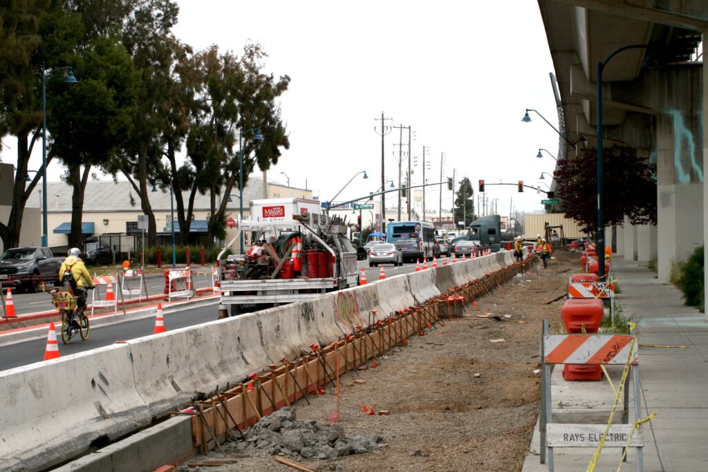 photo of a barricaded pathway construction site beneath the BART tracks on San Leandro St in Oakland