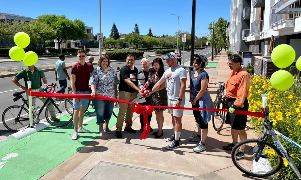 photo of Fremont elected officials and community members cutting a ceremonial ribbon for a new protected bikeway facility