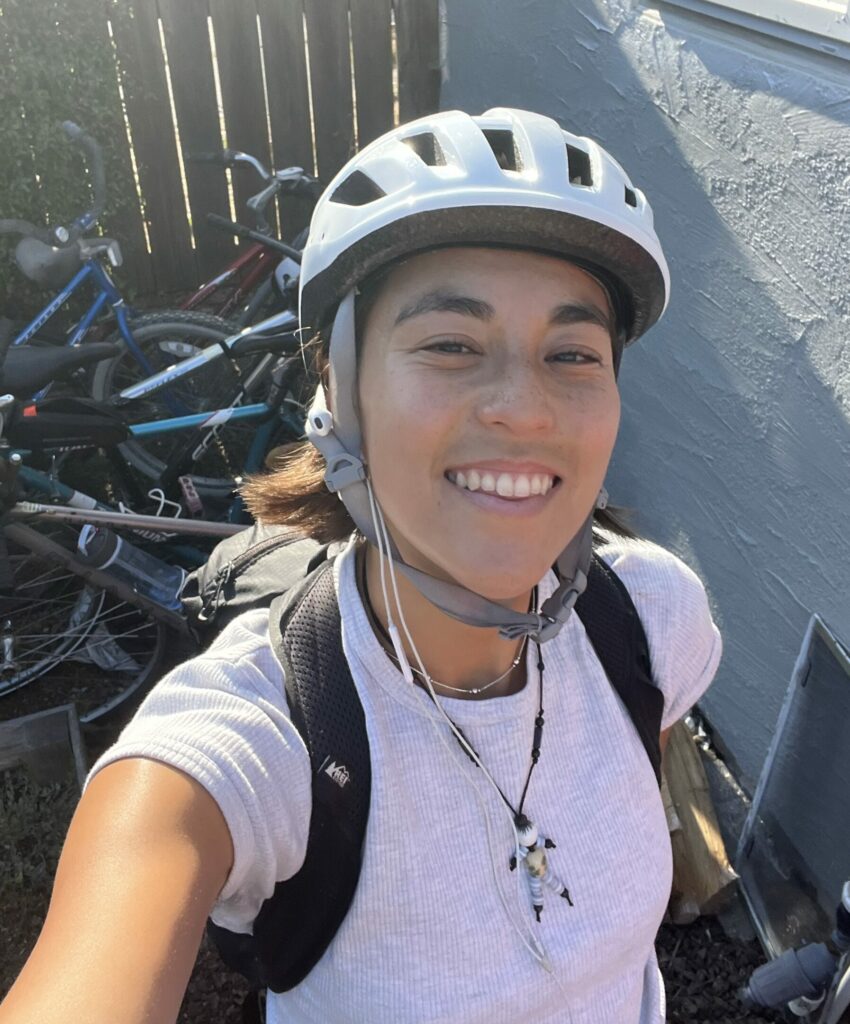 Photo of Elka in a white helmet and white shirt, smiling in a selfie