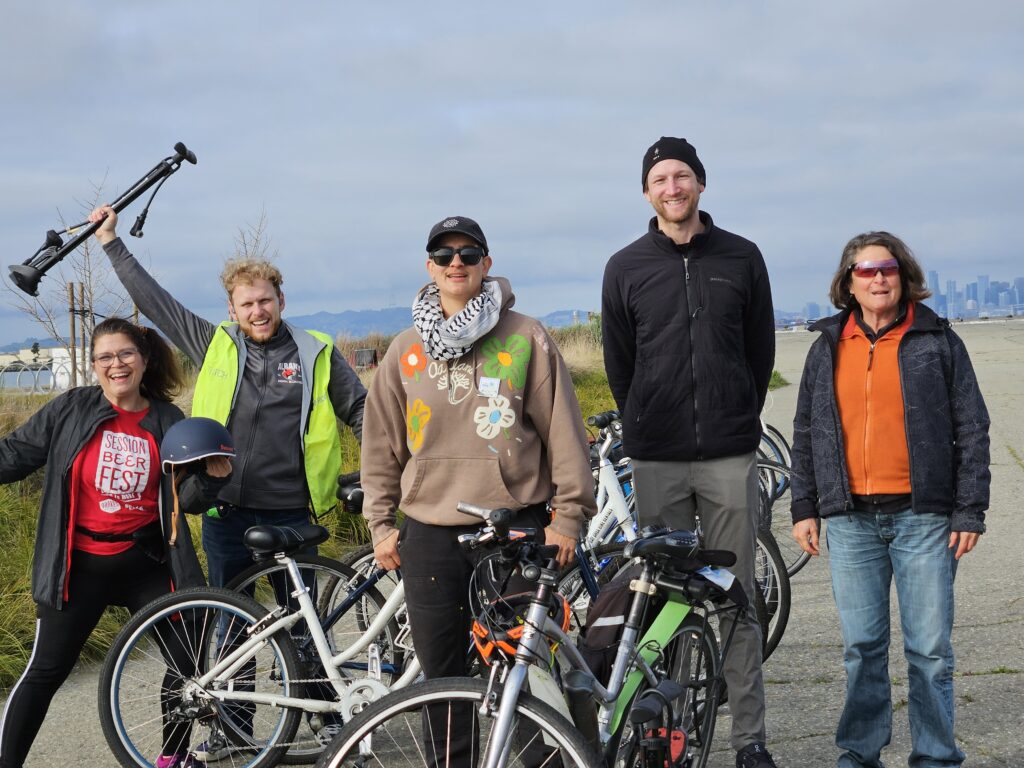 5 smiling people standing behind a few bikes