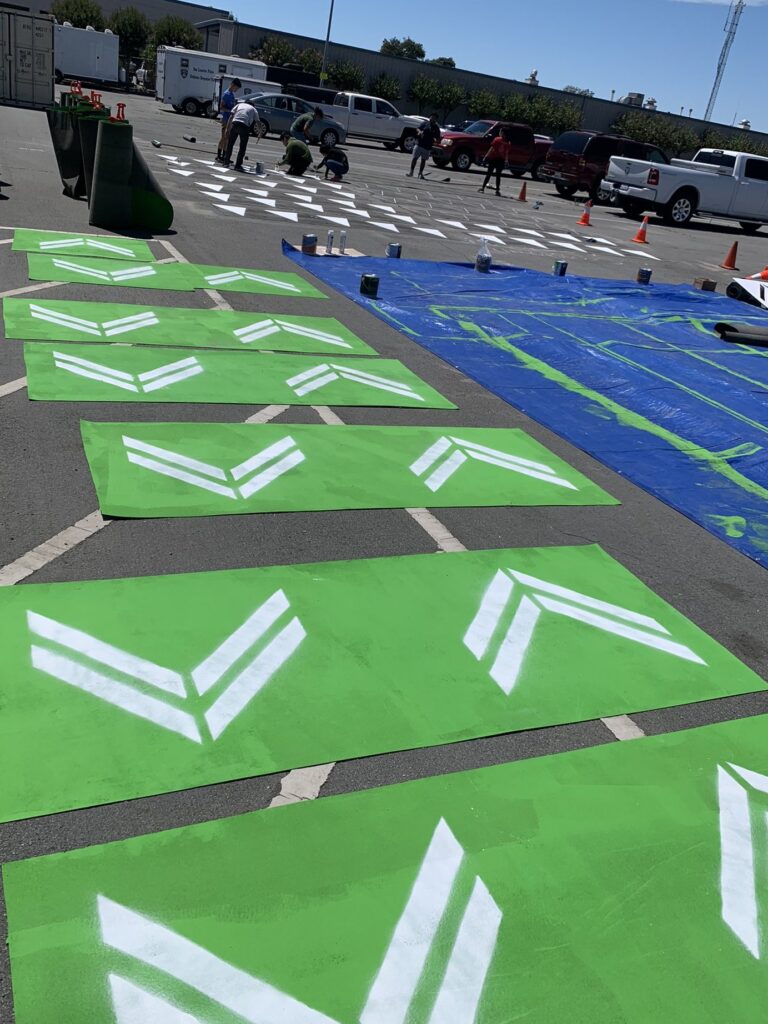 photo of people in a parking lot painting chevrons and other materials for use at a pop-up traffic safety demonstration project