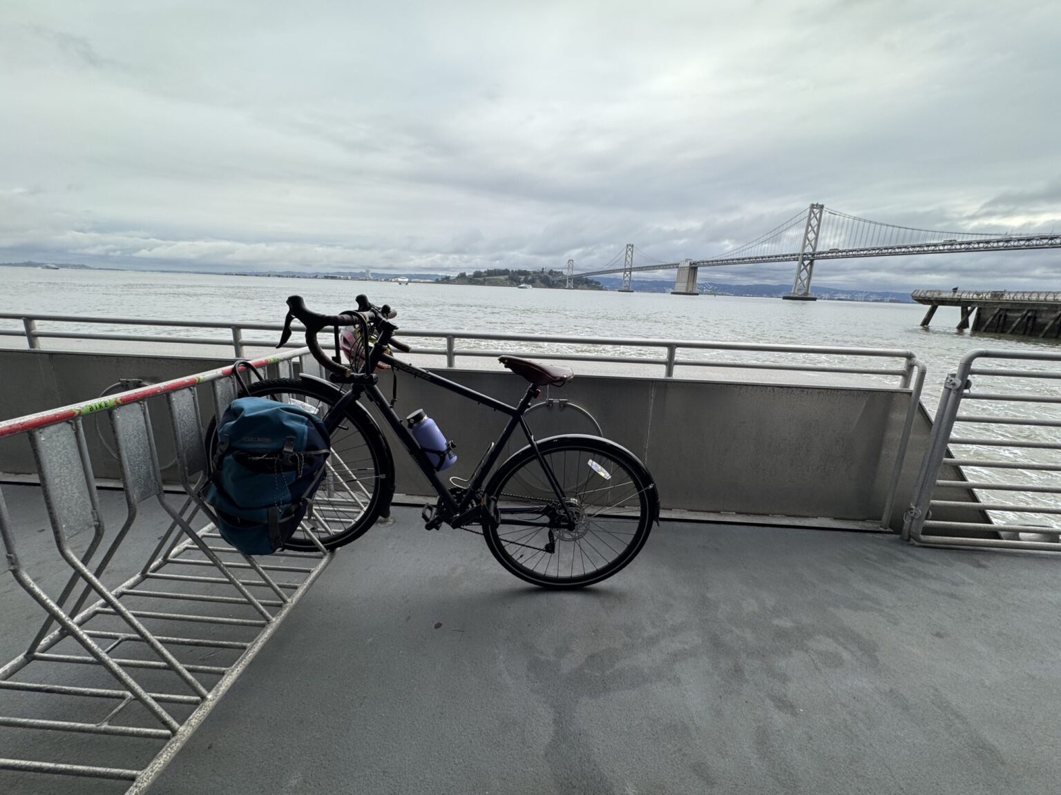 A bike is parked on-board an SF Bay Ferry, with the Bay Bridge in the background