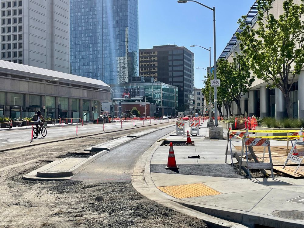 photo of a curbside protected bikeway under construction on 20th Street in Downtown Oakland