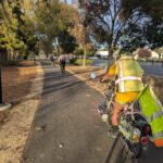 Photo of a line of bicyclists riding on a smoothly paved off-street landscaped trail