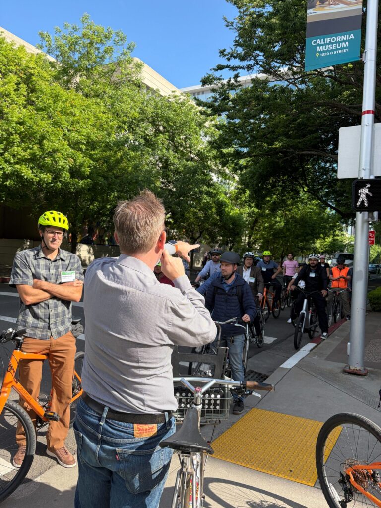 A speaker on a group ride gestures during a stop
