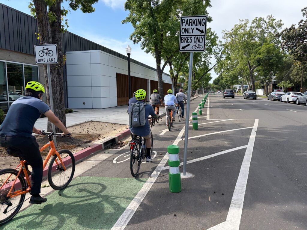 Group riders in a bike lane with plastic bollards