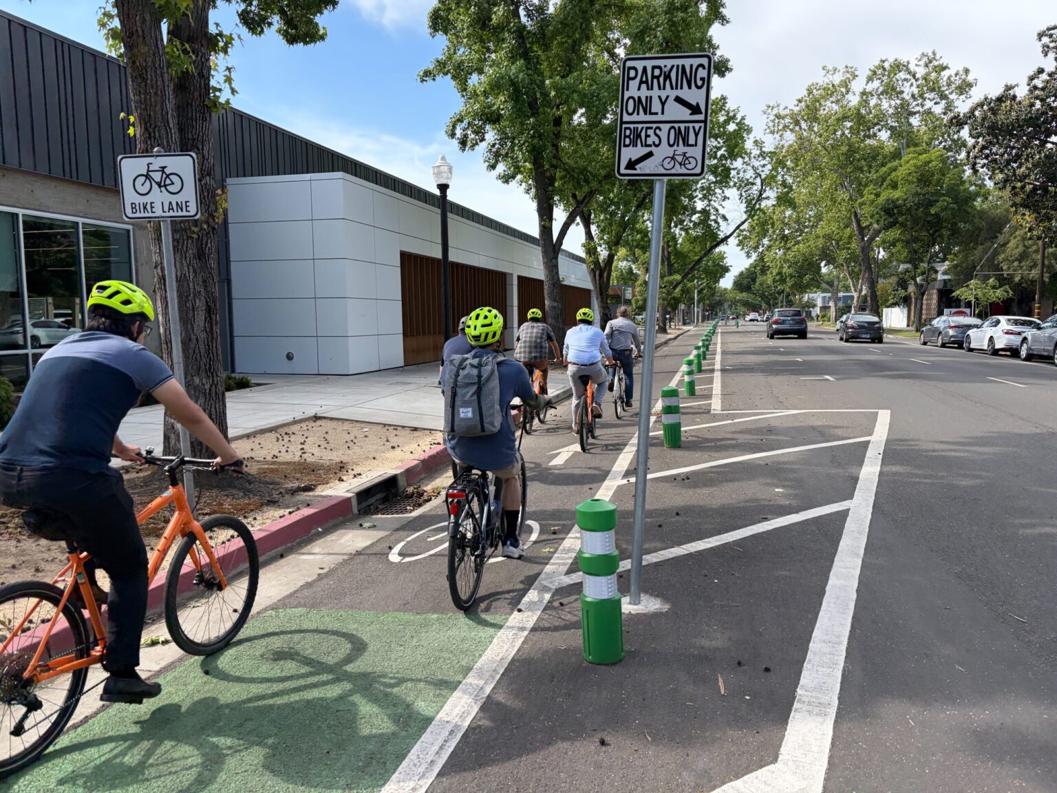 Group riders in a bike lane with plastic bollards
