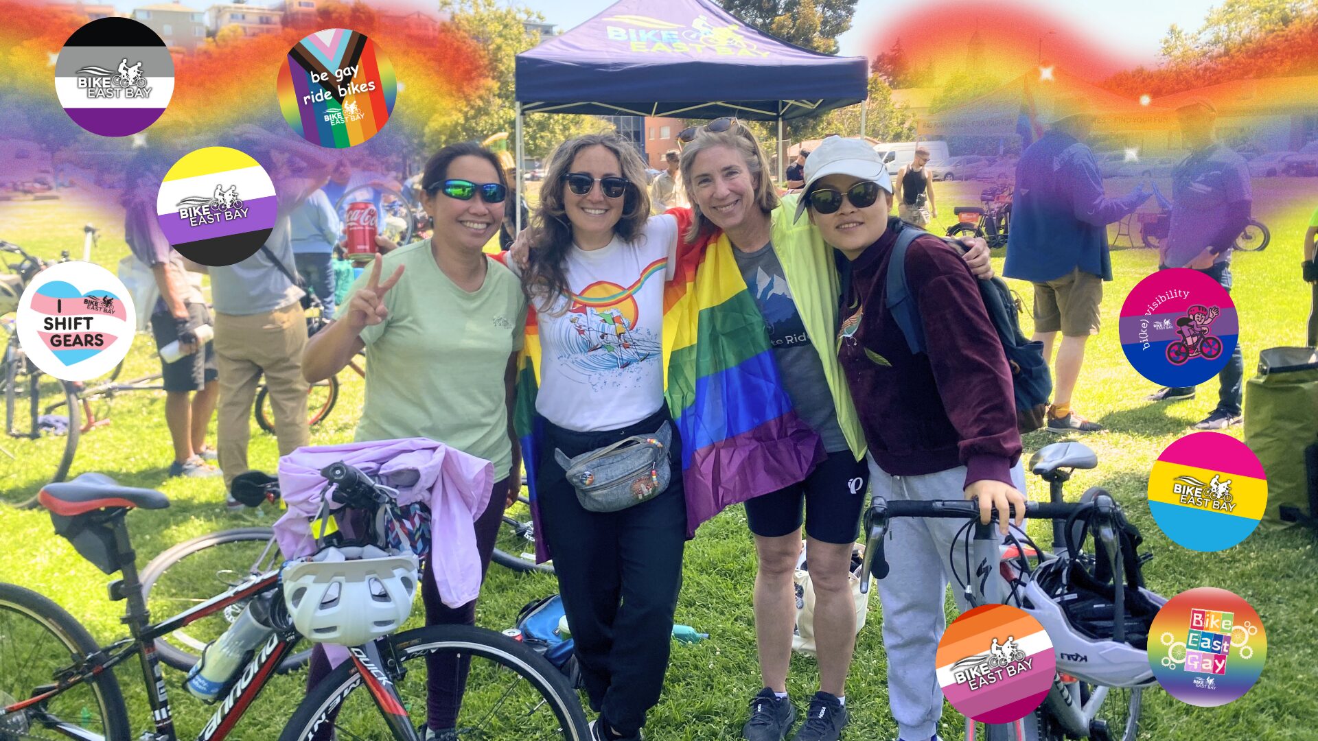 4 people smile with their bikes, dressed in Pride gear and with tons of rainbows and Pride graphics surrounding them.