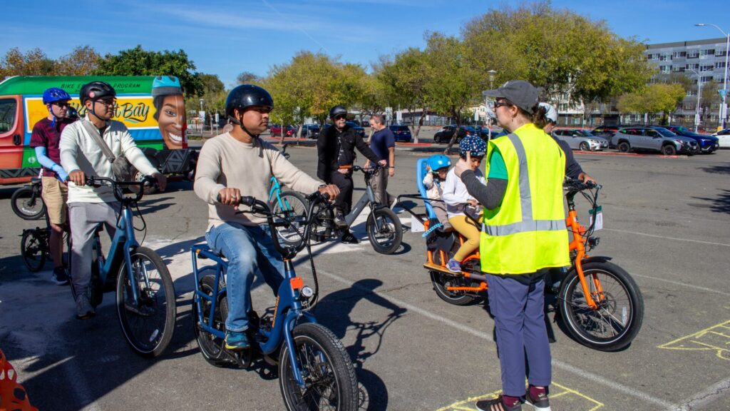 A group of people riding e-bikes wait at the start of a test track.